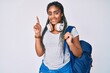 © Krakenimages.com - Young african american woman with braids wearing student backpack and headphones surprised with an idea or question pointing finger with happy face, number one