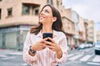 © Krakenimages.com - Young hispanic woman smiling happy using smartphone at the city.
