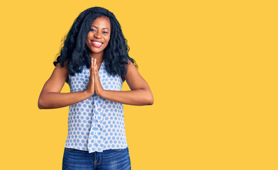 Wall Mural - Beautiful african american woman wearing casual summer shirt praying with hands together asking for forgiveness smiling confident.