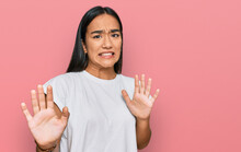 Young Asian Woman Wearing Casual White T Shirt Disgusted Expression, Displeased And Fearful Doing Disgust Face Because Aversion Reaction. With Hands Raised