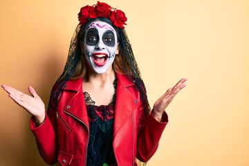 Sticker - Woman wearing day of the dead costume over yellow celebrating victory with happy smile and winner expression with raised hands