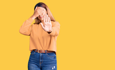 Sticker - Beautiful young woman wearing casual clothes covering eyes with hands and doing stop gesture with sad and fear expression. embarrassed and negative concept.