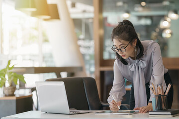 Leinwandbilder - Businesswoman working with a stylus pen on a digital tablet with a laptop computer in a modern office.