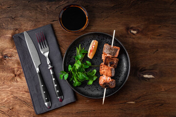  Baked salmon red fish kebab with lemon and herbs on wooden background, top view