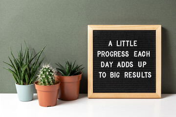 Wall Mural - A little progress each day adds up to big results. Motivational quote on letter board, cactus, succulent flower on white table. Concept inspirational quote of the day. Front view