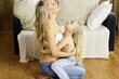 Happy mom and little daughter cuddle while dressing. Motherhood and family concept