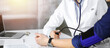 © rogerphoto - Unknown woman doctor is checking her patient's blood pressure while sitting together in sunny clinic. Medicine concept during Coronavirus pandemic