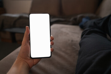 Poster - Man hold smartphone with white screen in his hand lying on a couch in home environment