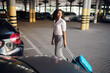 © Nomad_Soul - Young woman with suitcase in car parking