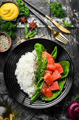 Wall Mural - Rice with red fish, green beans and spinach in a black plate. Diet. Top view. Free space for text.