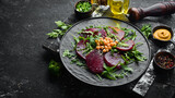 Fototapeta Mapy - Vegan salad: beets, arugula and chickpeas on a black stone plate. Healthy diet food. Top view. Free space for text.