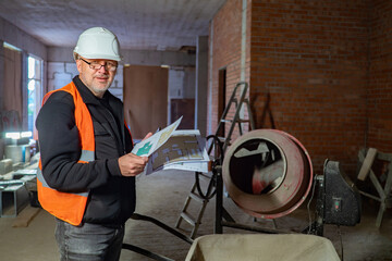 Poster - Builder inside the building under construction. The man with the drawings looks into the camera. Execution of construction orders on time. High quality of construction works.
