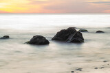 Fototapeta Morze - Beautiful sunset over Baltic sea with stones  in the water, long exposure photography.