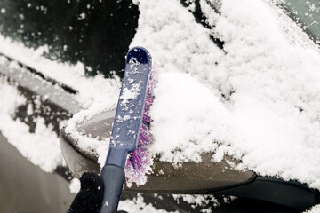 Wall Mural - Male driver sweeps snow off car mirror with special brush