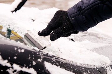 Wall Mural - A male driver cleans ice and snow off the car windscreen with a scraper