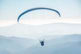 The paraglider is flying in the sky.