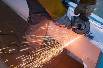 Poster - Cutting metal with a grinder. A man cuts steel sheet with an electric machine. Grinder in the master hands and sparks from cutting metal. Hand-held power tools for metal processing.