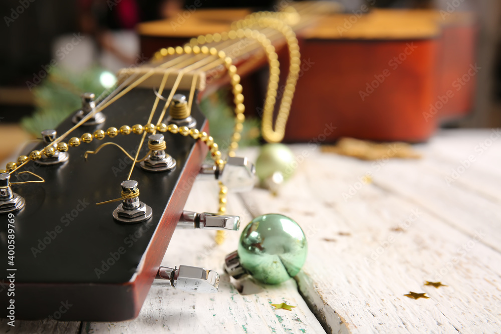 Guitar with Christmas decor on white wooden background, closeup