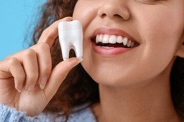 Poster - Beautiful young woman with model of tooth on color background, closeup