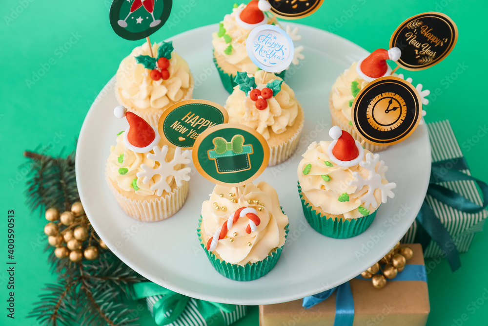 Dessert stand with tasty Christmas cupcakes on color background