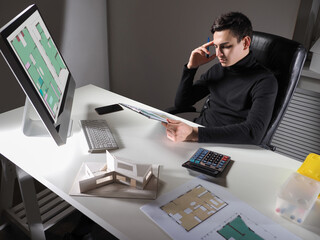 Poster - Work on a project of the new house. Civil engineer sits at his desk and looks at the drawings. Architect studies the floor plans. The man works in an architectural and construction bureau.