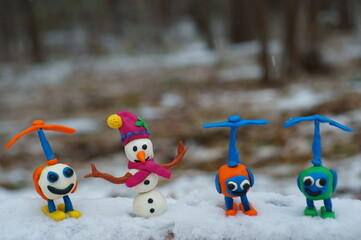 Wall Mural - Figure of a snowman in a red hat made of plasticine. near toy helicopters.