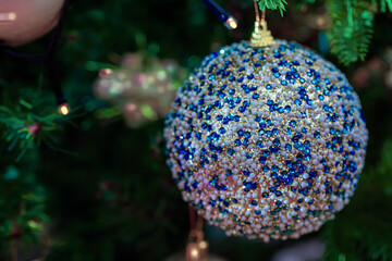 Wall Mural - Christmas ball with blue glass stones on a festive tree. Dark blurred background. Shallow depth of field. Macro.