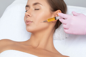 cosmetologist does prp therapy on the face of a beautiful woman in a beauty salon. cosmetology conce