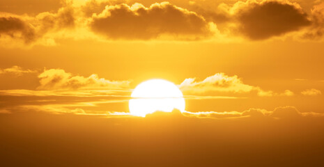 Wall Mural - sunset with a bright, big and clear sun over the clouds in an orange sky