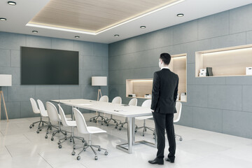 Sticker - Businessman standing in meeting interior room with blank plasma screen