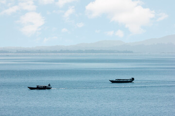  Passenger boats moving through vast river and hills in the background