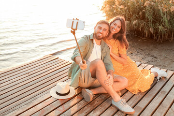 Wall Mural - Young couple taking selfie near river