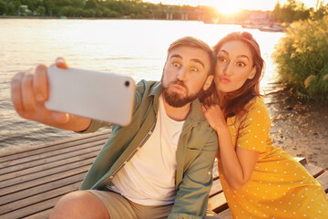 Canvas Print - Young couple taking selfie near river