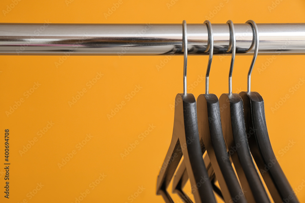 Rack with clothes hangers on color background, closeup