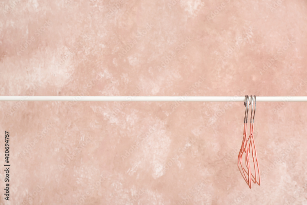 Rack with clothes hangers on color background