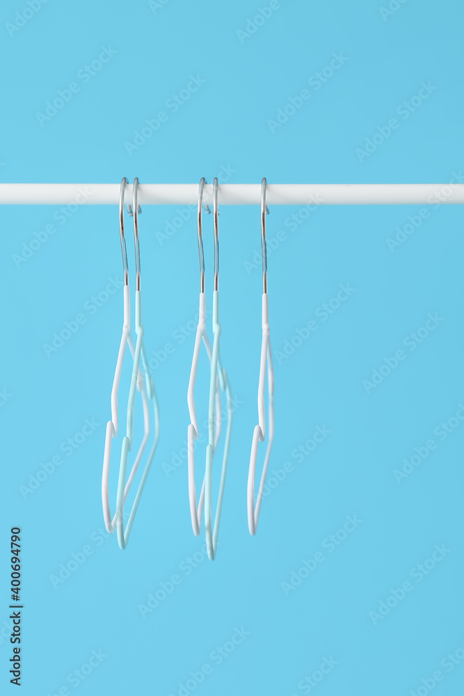 Rack with clothes hangers on color background