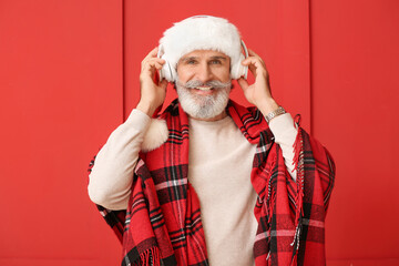 Sticker - Senior man listening to Christmas music on color background