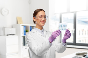 Sticker - science, chemistry and people concept - happy smiling young female scientist in goggles with chemical sample or vaccine over laboratory background