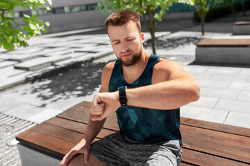 Poster - sport, technology and fitness concept - young man with smart watch sitting on bench