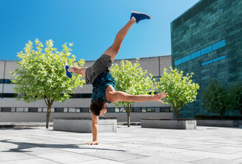 Sticker - fitness, sport, training and lifestyle concept - young man exercising and doing handstand on one arm outdoors