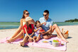 © Syda Productions - family, leisure and people concept - happy mother, father and two daughters having picnic on summer beach and eating strawberries