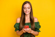 © deagreez - Close-up portrait of attractive focused cheery long-haired girl influencer using device chatting isolated over bright yellow color background