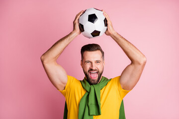 Poster - Photo of happy soccer man fan hold ball above head celebrate win isolated on pastel pink color background