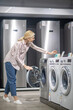 © zinkevych - Woman in striped shirt choosing a washing machine in a showroom and looking interested
