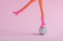 Creative  Party Time Concept With Woman Legs And Disco Ball On Pastel Pink Background.