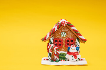 Poster - toy christmas house with a snowman on a yellow background