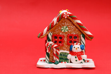 Poster - toy christmas house with a snowman on a red background