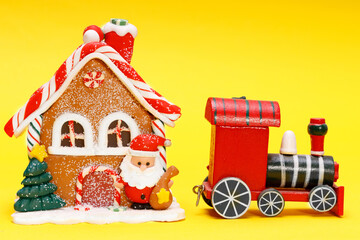 Poster - toy christmas house with santa claus train on a yellow background