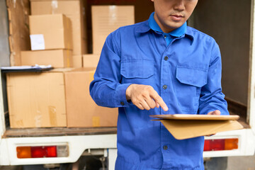 Wall Mural - Cropped image of serious courier checking information on digital tablet after deliverying packages to address