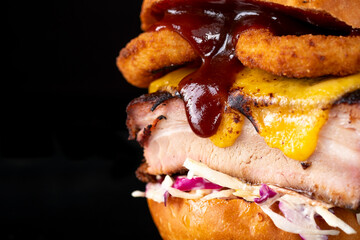 Pulled pork burger with onion rings, cheese, cabbage and lettuce. Macro view